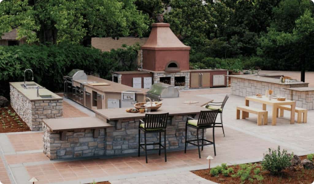 Outdoor kitchen with stone accents and a built-in grill, perfect for outdoor living and entertaining, surrounded by lush greenery.