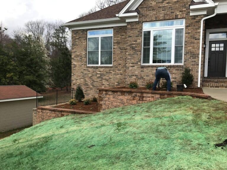 Beautiful backyard landscaping with a tiered stone retaining wall, freshly planted shrubs, and a lush green lawn enhancing outdoor living space. Perfect for outdoor entertaining and relaxing.