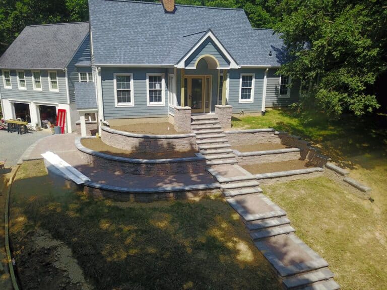 Elegant outdoor living space with multi-level stone patio, stairs, and retaining walls for enhanced backyard design and functionality.
