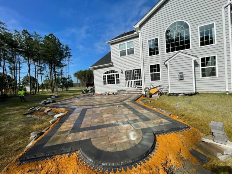 Modern outdoor living space featuring a stylish patio with stone pavers and a curved design, perfect for relaxing and entertaining in your backyard. Outdoor seating area upcoming.