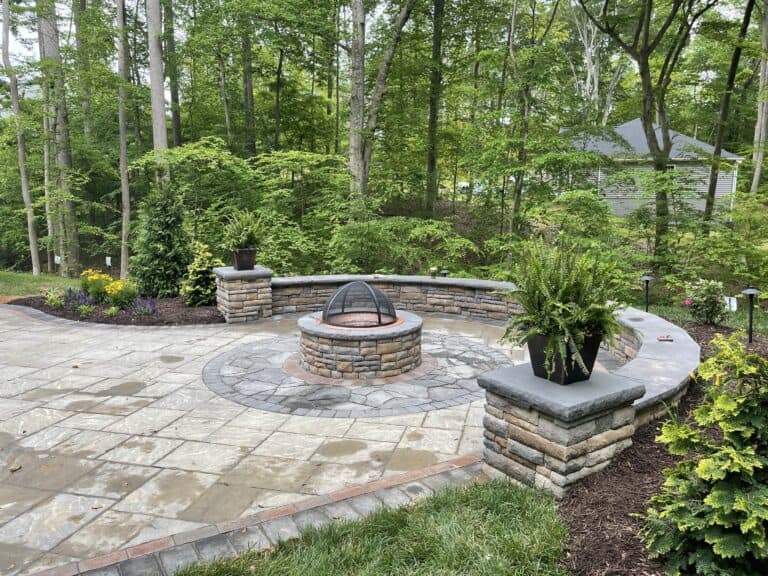 Stone fire pit with outdoor seating area and lush greenery in a backyard garden, perfect for outdoor living spaces and entertaining.