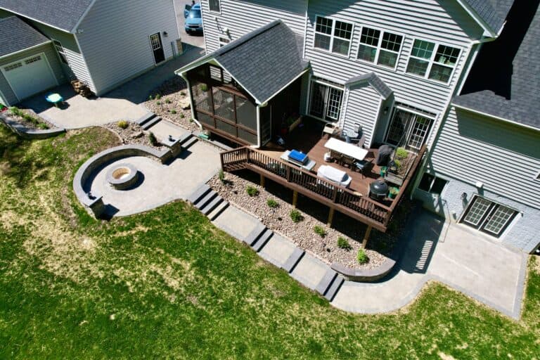 Beautiful backyard outdoor living space featuring a spacious wooden deck, cozy fire pit area, and lush green lawn, perfect for entertaining and relaxation.