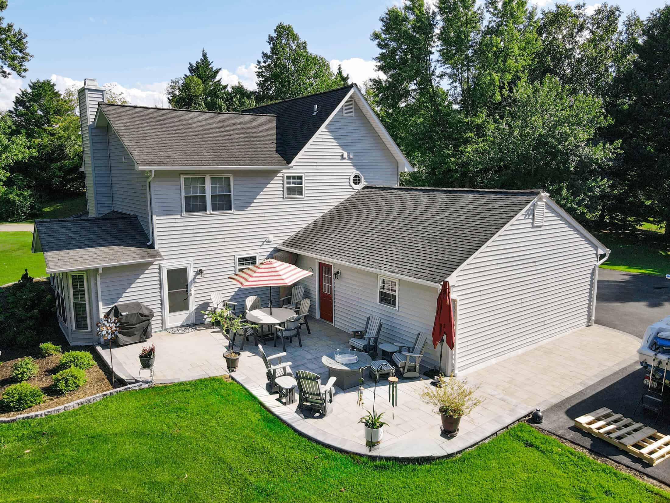 Modern white house with a spacious outdoor living space featuring a beautifully designed patio, outdoor furniture, and lush greenery for relaxing and entertaining.