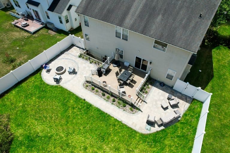 Spacious backyard outdoor living space with patio, fire pit, dining area, and lounge chairs, perfect for outdoor entertainment and relaxing.