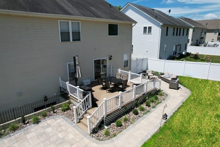 Spacious outdoor living space with a deck, outdoor dining area, and comfortable seating perfect for entertaining and relaxation. Enhances home value through outdoor living spaces and stylish backyard design.