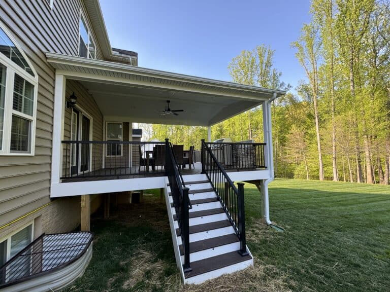 Modern screened-in outdoor living space with a spacious deck, stylish railing, and outdoor furniture, ideal for relaxing and entertaining amidst lush green surroundings.