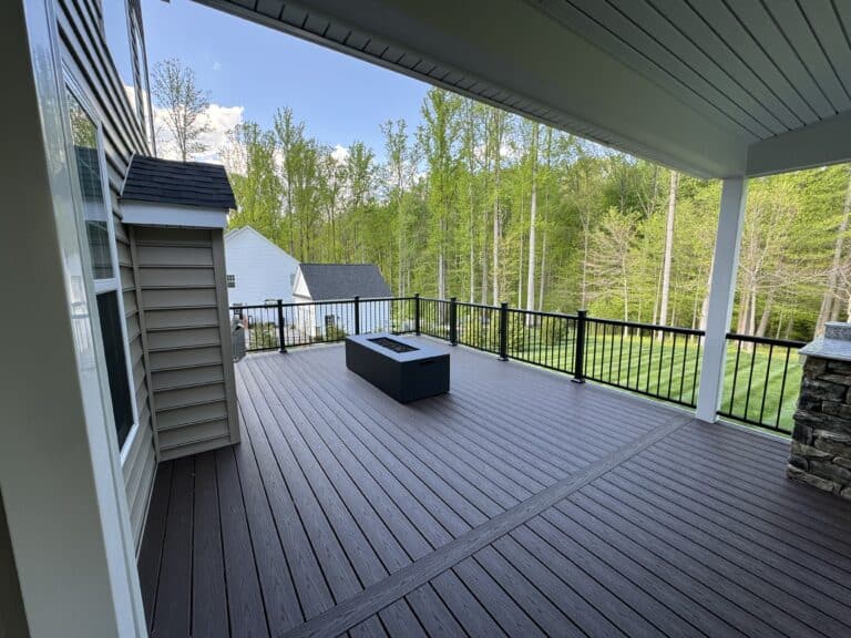 Spacious outdoor deck with modern black railing, surrounded by lush green trees, perfect for outdoor living and entertaining.