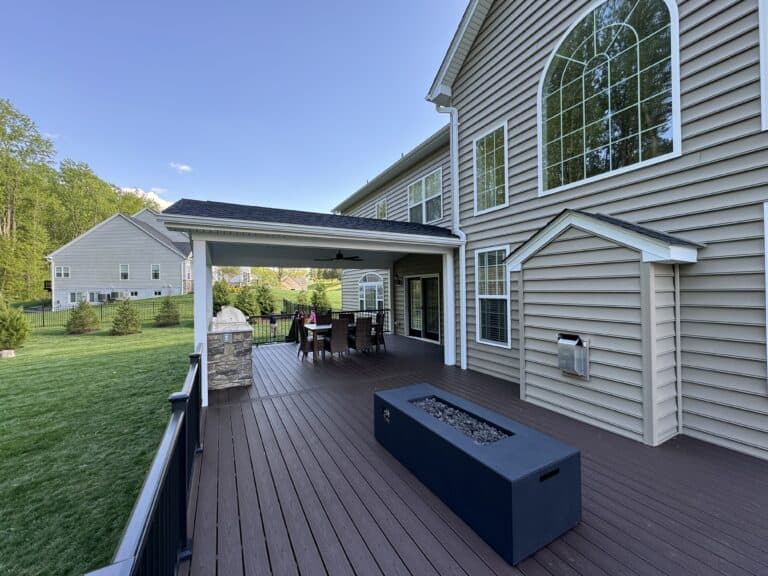 Stylish outdoor living space with a spacious deck, dining area, and modern fire feature, perfect for relaxing and entertaining in a beautifully landscaped backyard.