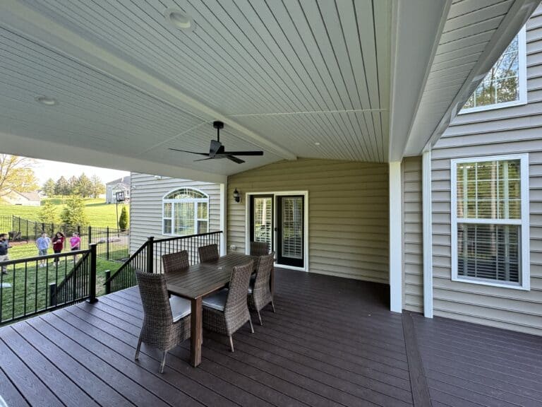 Stunning covered outdoor patio with a modern ceiling fan, dining area, and scenic backyard view, perfect for outdoor living and entertaining.