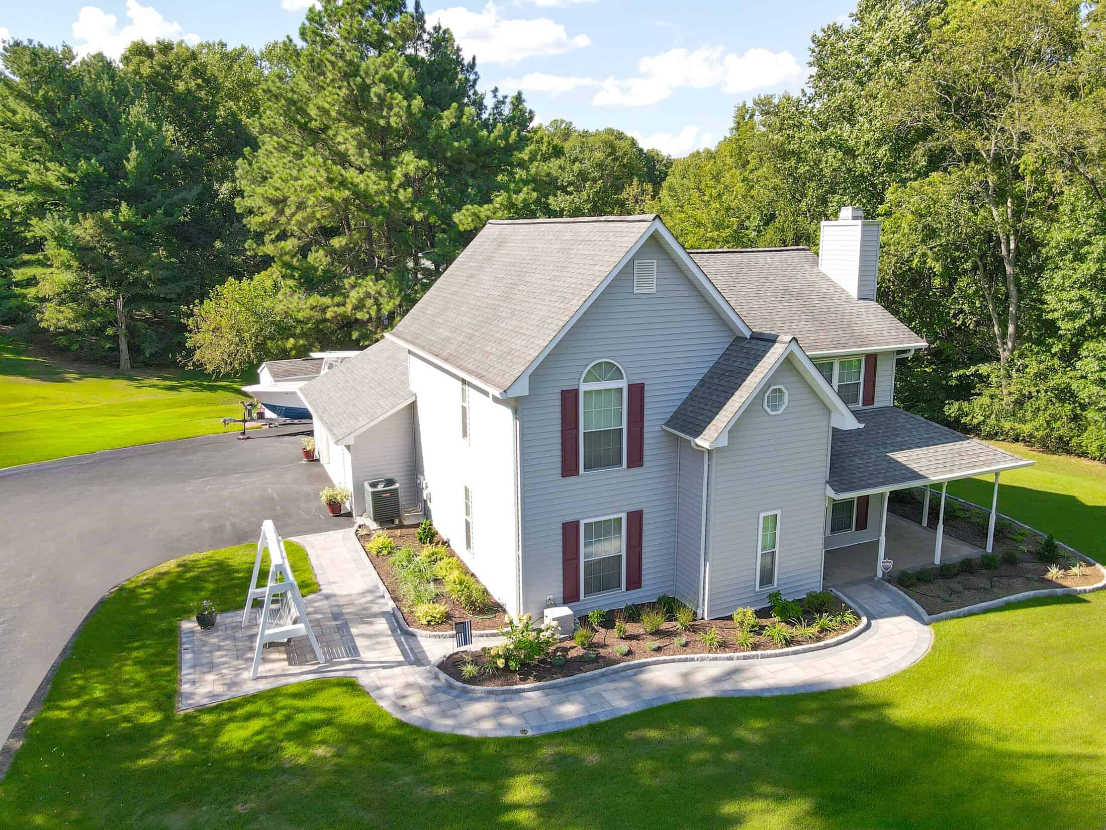 Spacious backyard with a well-maintained lawn, beautiful landscaping, and a paved outdoor seating area surrounding a swing, perfect for outdoor living and entertaining.