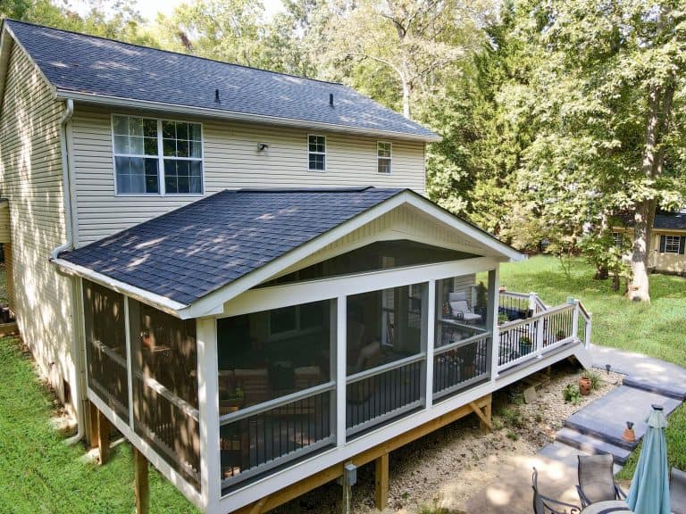 Beautiful backyard outdoor living space with a screened-in porch, surrounded by lush greenery and mature trees, perfect for relaxing and entertaining.