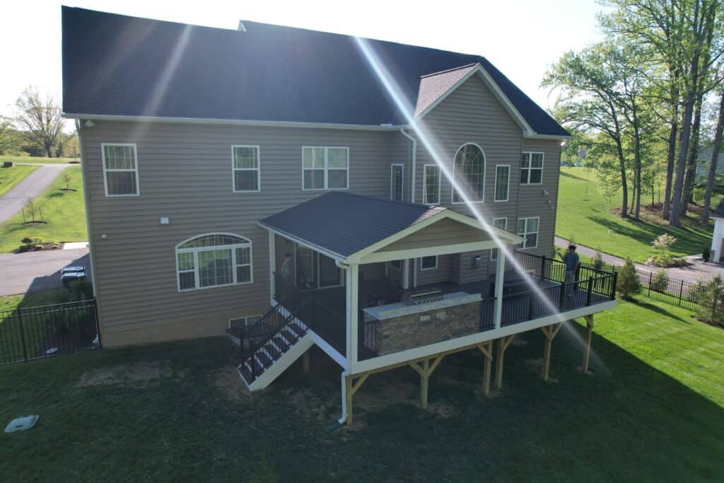 Spacious outdoor deck with a covered dining area, built for outdoor living and entertaining, featuring stylish railings and a view of lush green yard and landscaping.