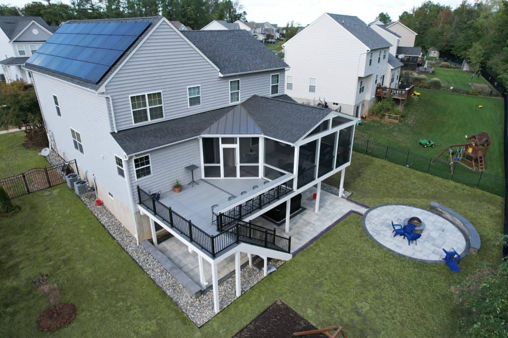 Spacious outdoor living space featuring a multi-level deck with a screened porch, perfect for relaxing and entertaining in a family home. The backyard includes a fire pit, play area, and lush green lawn.