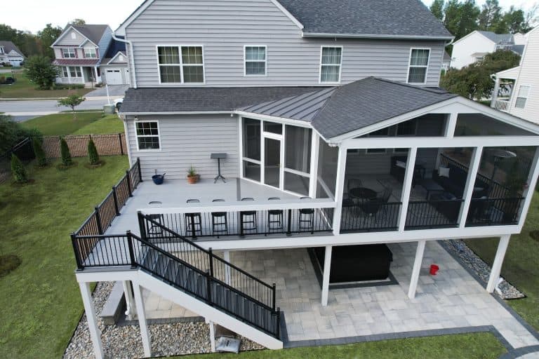 Stunning outdoor living space with a spacious multi-level deck, black metal railings, and a screened-in porch, perfect for relaxing and entertaining in your backyard.