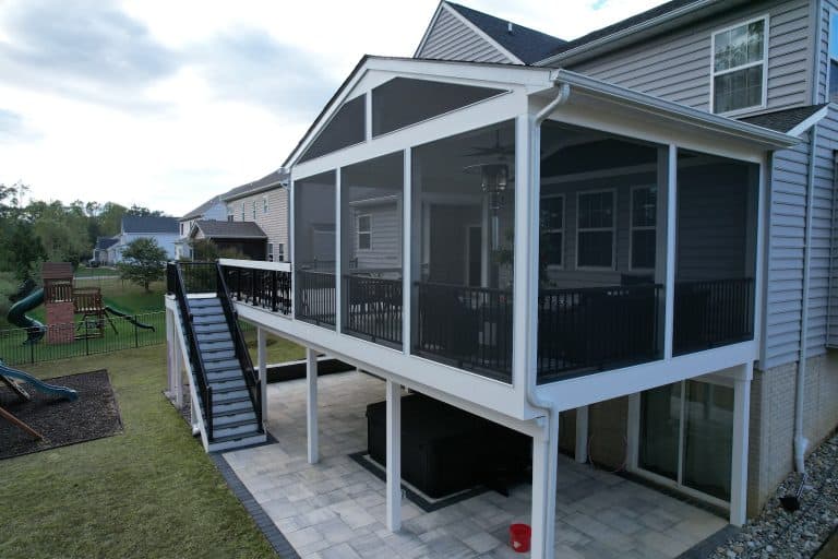 Modern screened outdoor living space with elevated deck, black railing, and outdoor furniture, ideal for relaxing and entertaining.