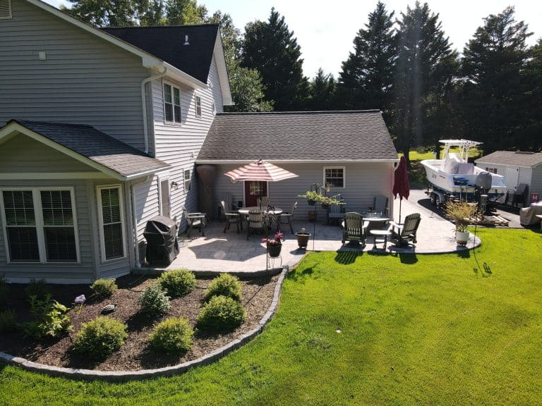 Outdoor living space with a spacious patio featuring outdoor furniture, a gazebo, and a boat parked nearby, designed for relaxing and entertaining in a beautiful backyard setting.