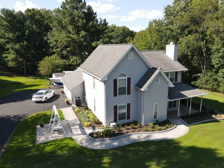 Modern farmhouse-style house with a spacious backyard, landscaped garden, and paved pathway, perfect for outdoor living and entertaining.