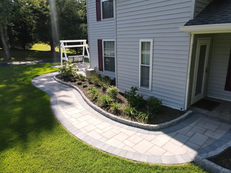 Elegant outdoor living space with a curved paver patio and lush landscaping, perfect for relaxing and entertaining. Custom-designed outdoor spaces enhance home beauty and functionality.