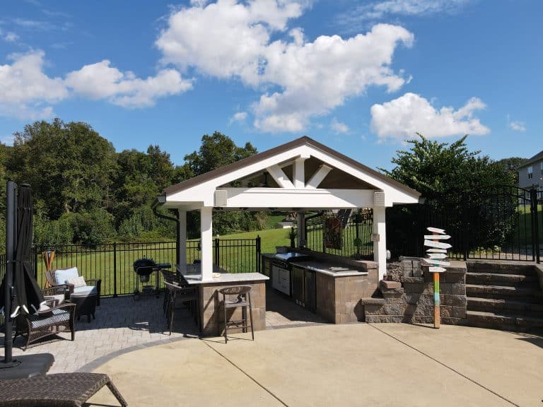 Outdoor living space with a built-in outdoor kitchen and seating area under a stylish gable roof, perfect for relaxing and entertaining in a private backyard setting.