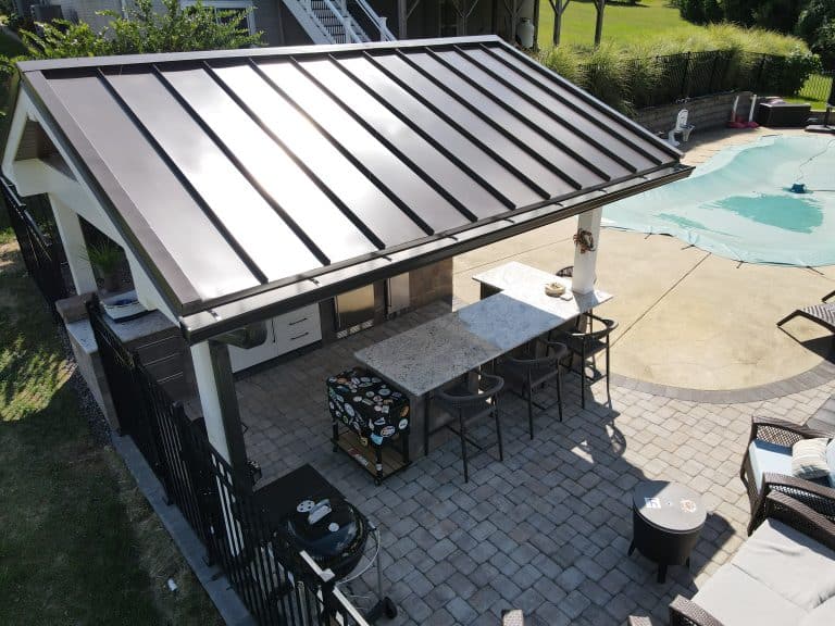 Modern outdoor kitchen with a sleek stone countertop, stainless steel appliances, and a stylish metal roof, perfect for outdoor living and entertaining.