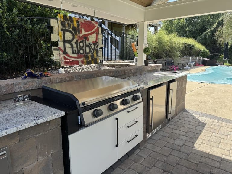 Modern outdoor kitchen with stainless steel grill and granite countertops in a stylish backyard outdoor living space.