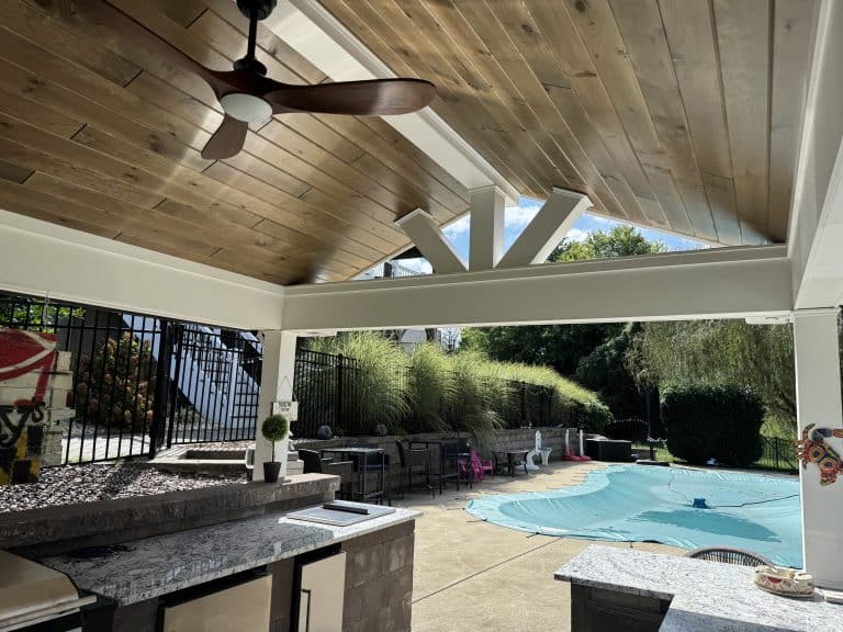 Modern outdoor living space with a stylish covered patio, ceiling fan, and pool area, perfect for relaxing and entertaining. Features durable materials, lush surroundings, and functional design for outdoor enjoyment.