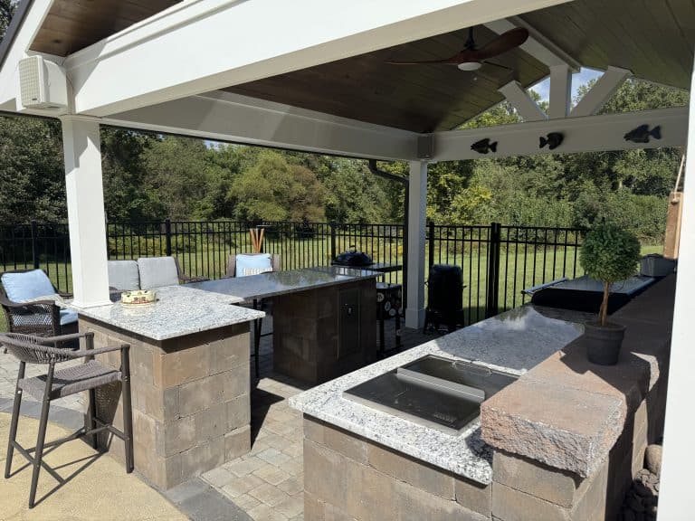 Modern outdoor kitchen with granite countertops, bar seating, and a covered patio perfect for relaxing and entertaining in a spacious backyard.