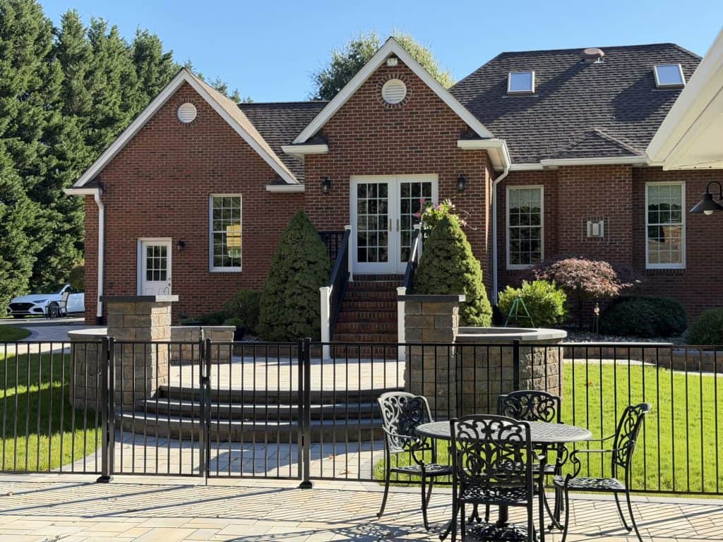 Beautiful brick house with a spacious outdoor patio, garden, and seating area, perfect for outdoor living and entertaining.