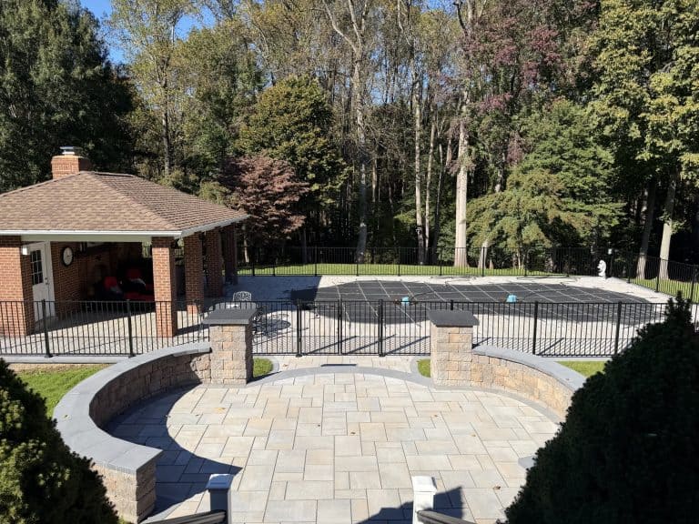 Beautiful backyard outdoor living space featuring a swimming pool, paved patio, and surrounding lush greenery for relaxation and entertainment.