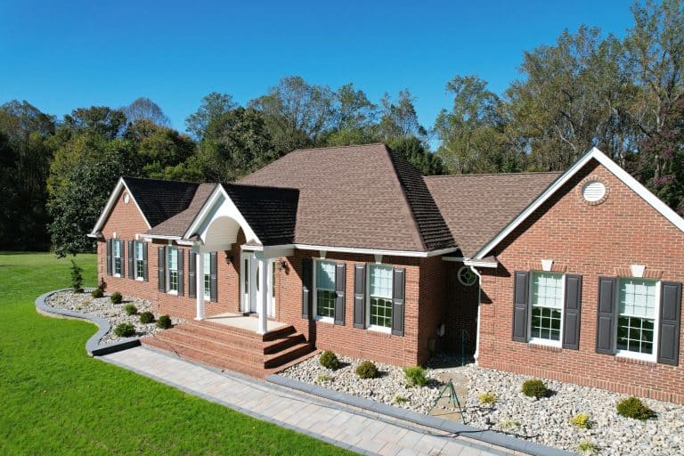 Beautiful brick house with a spacious outdoor living area, lush green lawn, and landscaped garden, perfect for outdoor entertaining and relaxation.
