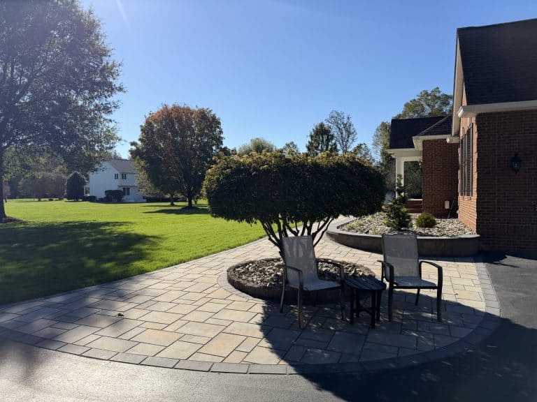 Elegant outdoor patio with seating area, lush trees, and well-maintained lawn, perfect for outdoor relaxation and entertaining.